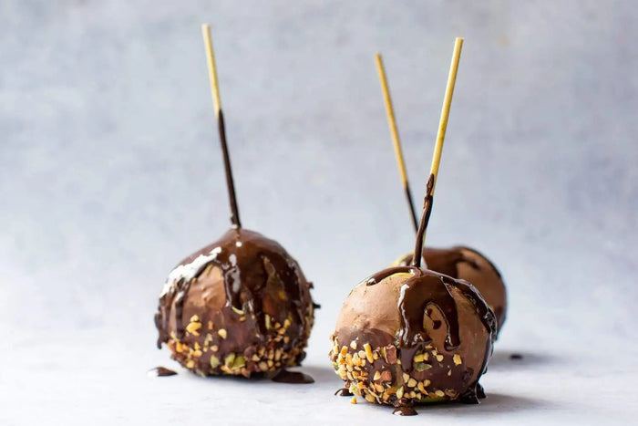 Chocolate-dipped apples on skewers with nuts and seeds