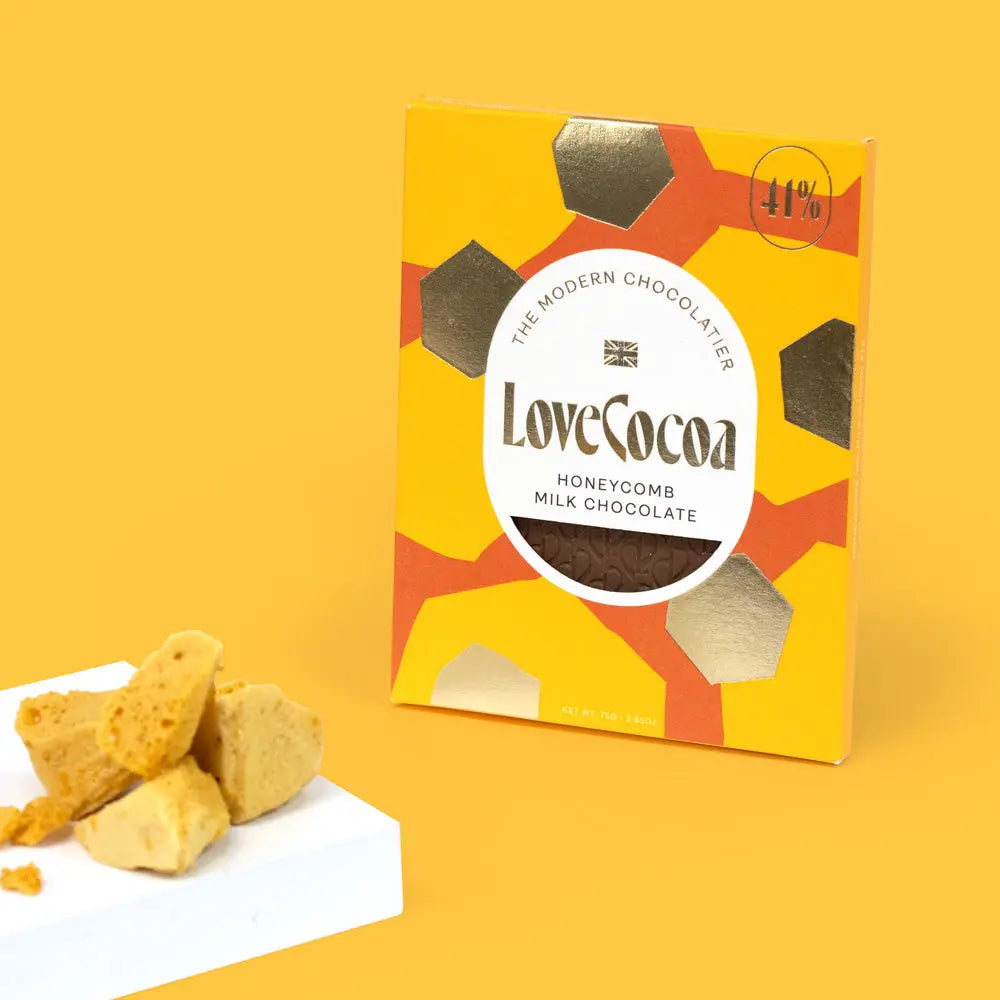 Love Cocoa Honeycomb 41% Milk Chocolate Bar, pack with pieces of honeycomb on a yellow background