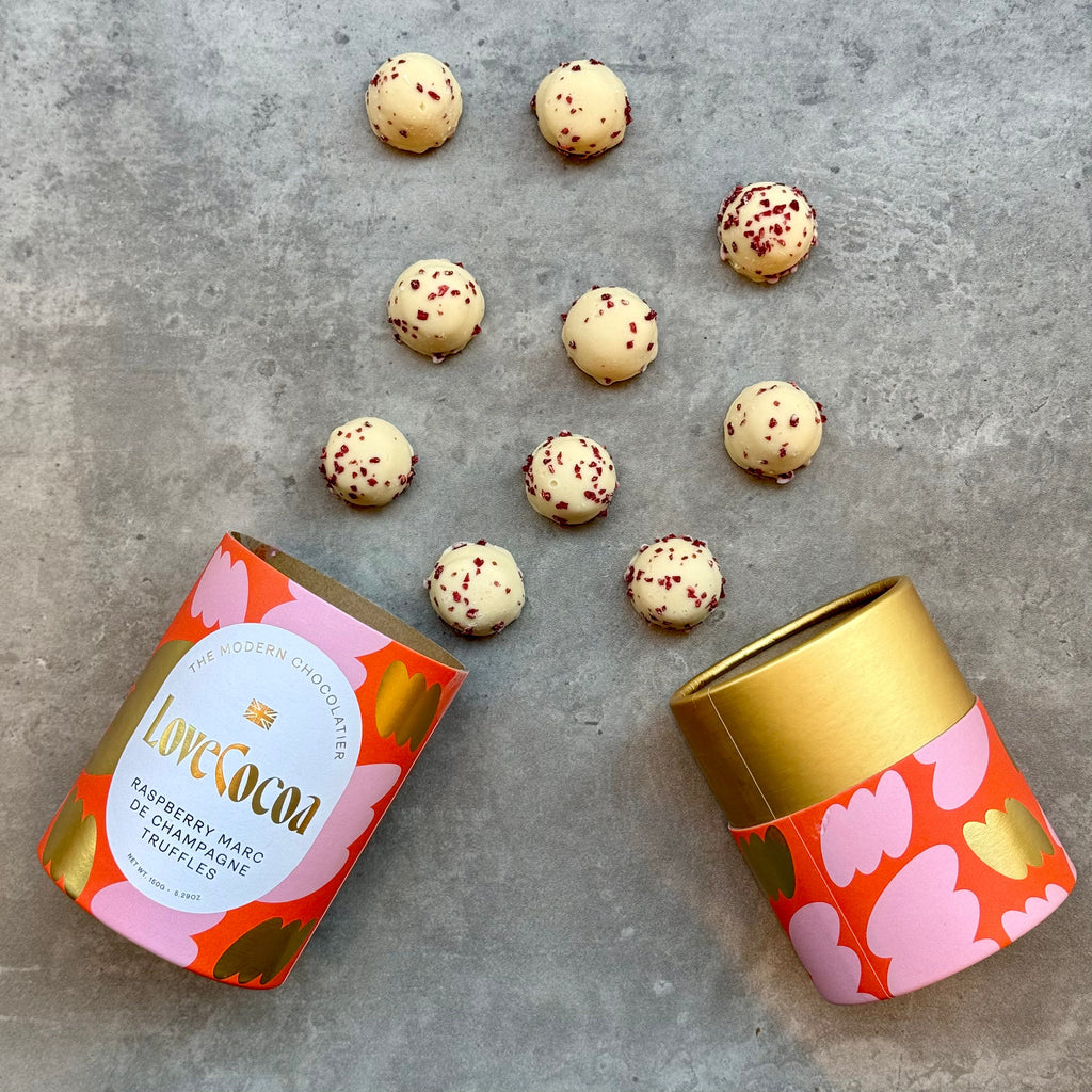 Love Cocoa Raspberry Marc de Champagne White Chocolate Truffles, open truffle tube with truffles scattered