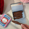 Love Cocoa Milk Chocolate Sardines Tin, open tin of chocolate sardines held in hand