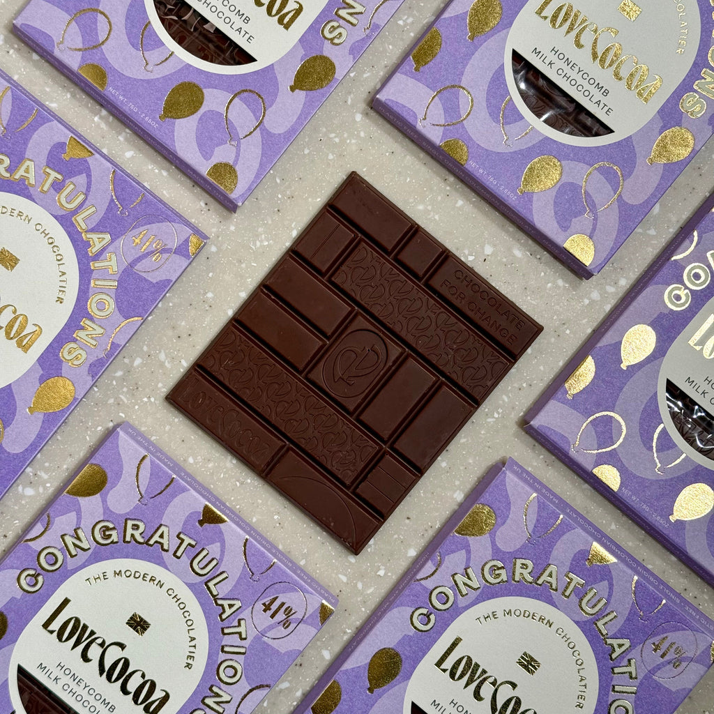 Love Cocoa Congratulations Honeycomb Milk Chocolate Bar, unwrapped bar on a stack of Congratulations packs