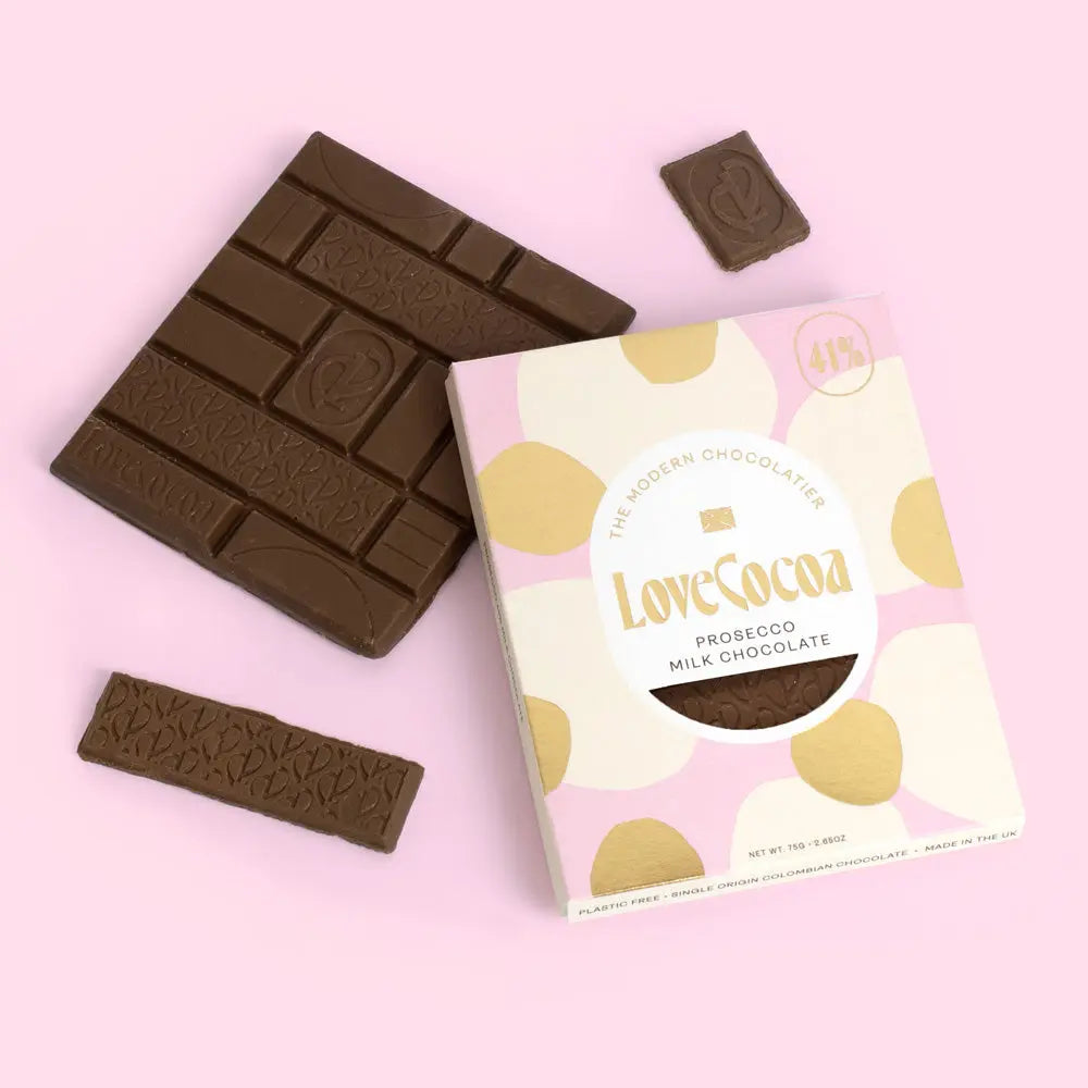 Love Cocoa Prosecco 41% Milk Chocolate Bar, pack with milk chocolate pieces on a pink background