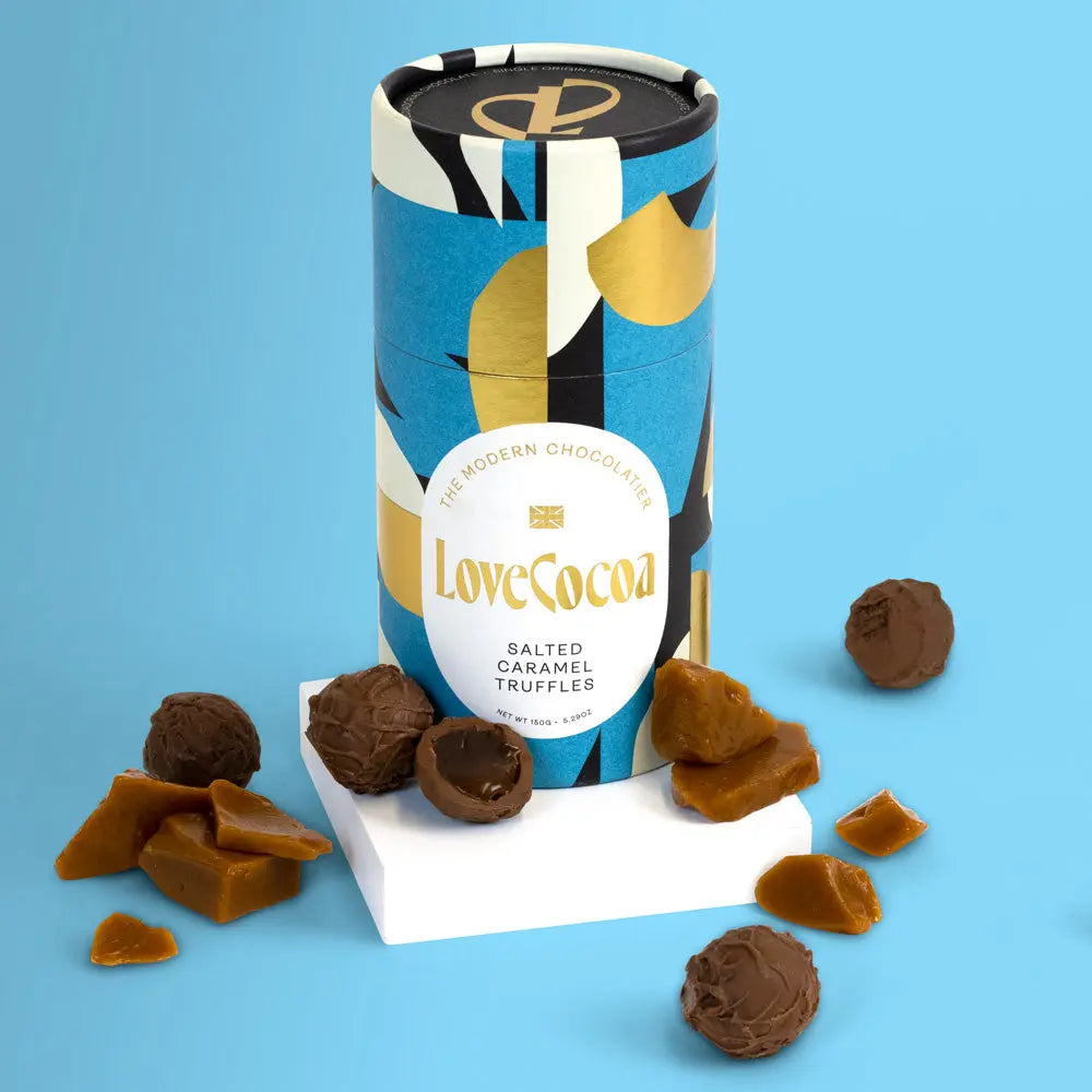Love Cocoa Salted Caramel Milk Chocolate Truffles, truffle tube with truffles and caramel pieces on a blue background