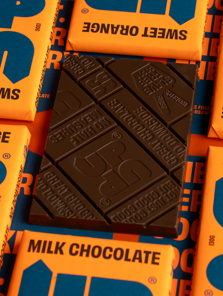 UP-UP Sweet Orange Milk Chocolate 120g, unwrapped bar showing chocolate squares on a stack of packs