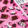 H!P Cookies NO Cream Oat M!lk Chocolate bar, chocolate squares and cookie pieces on a pink background