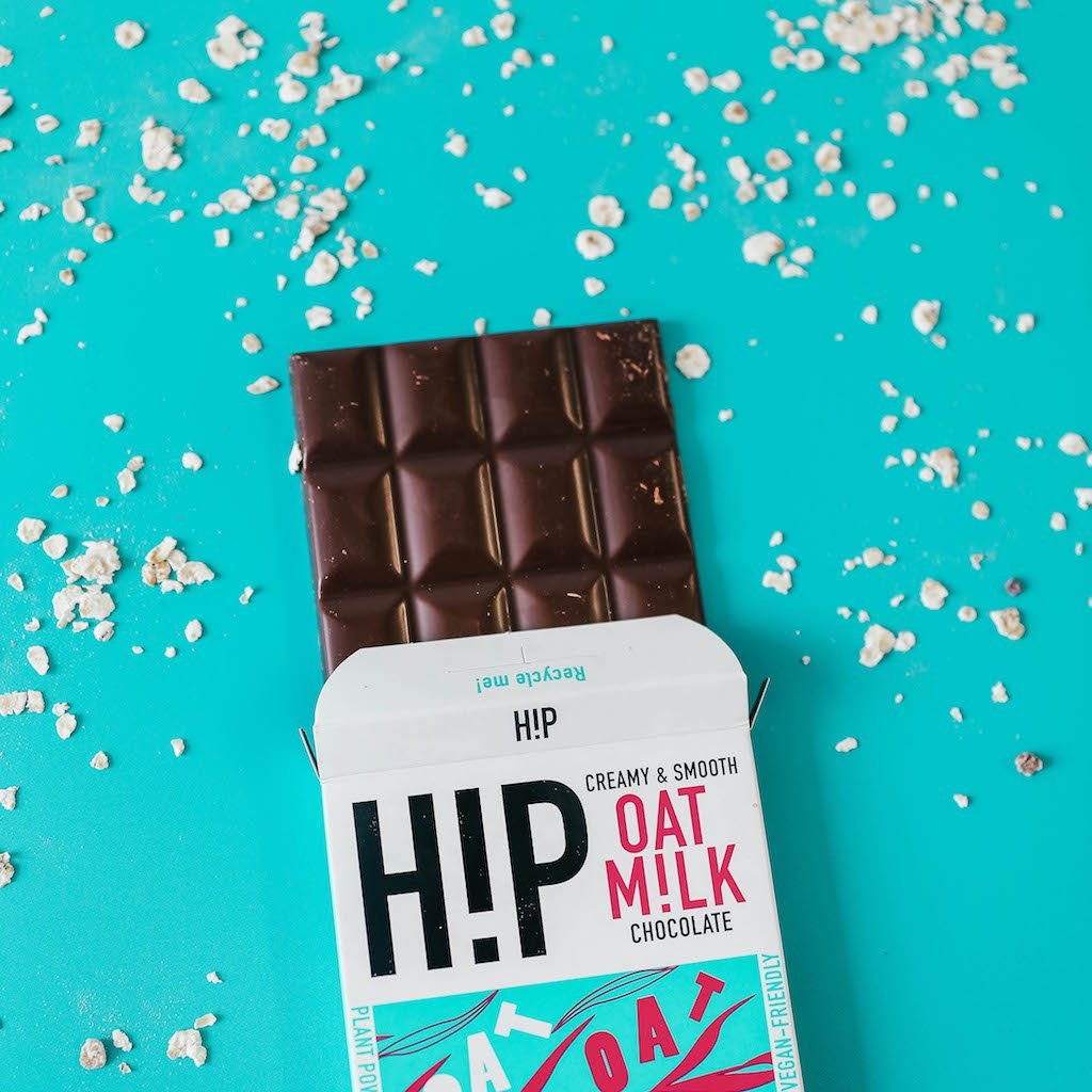 H!P Creamy Original Oat M!lk Chocolate bar, bar half out of its wrapper on a turquoise background