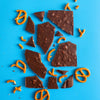 H!P Salty Pretzel Oat M!lk Chocolate bar, broken chocolate pieces with pretzels on a blue background